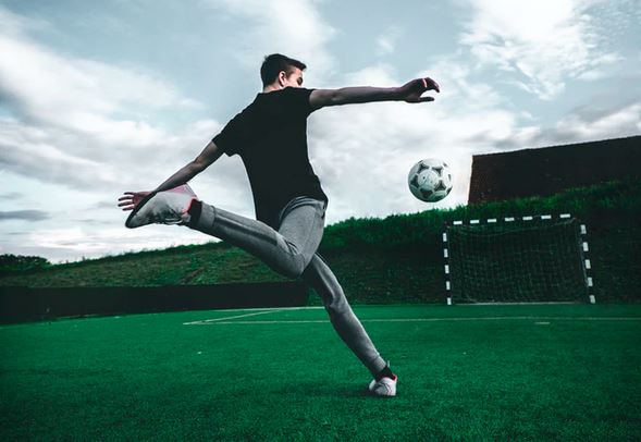 homme en survetement frappe dans un ballon de foot